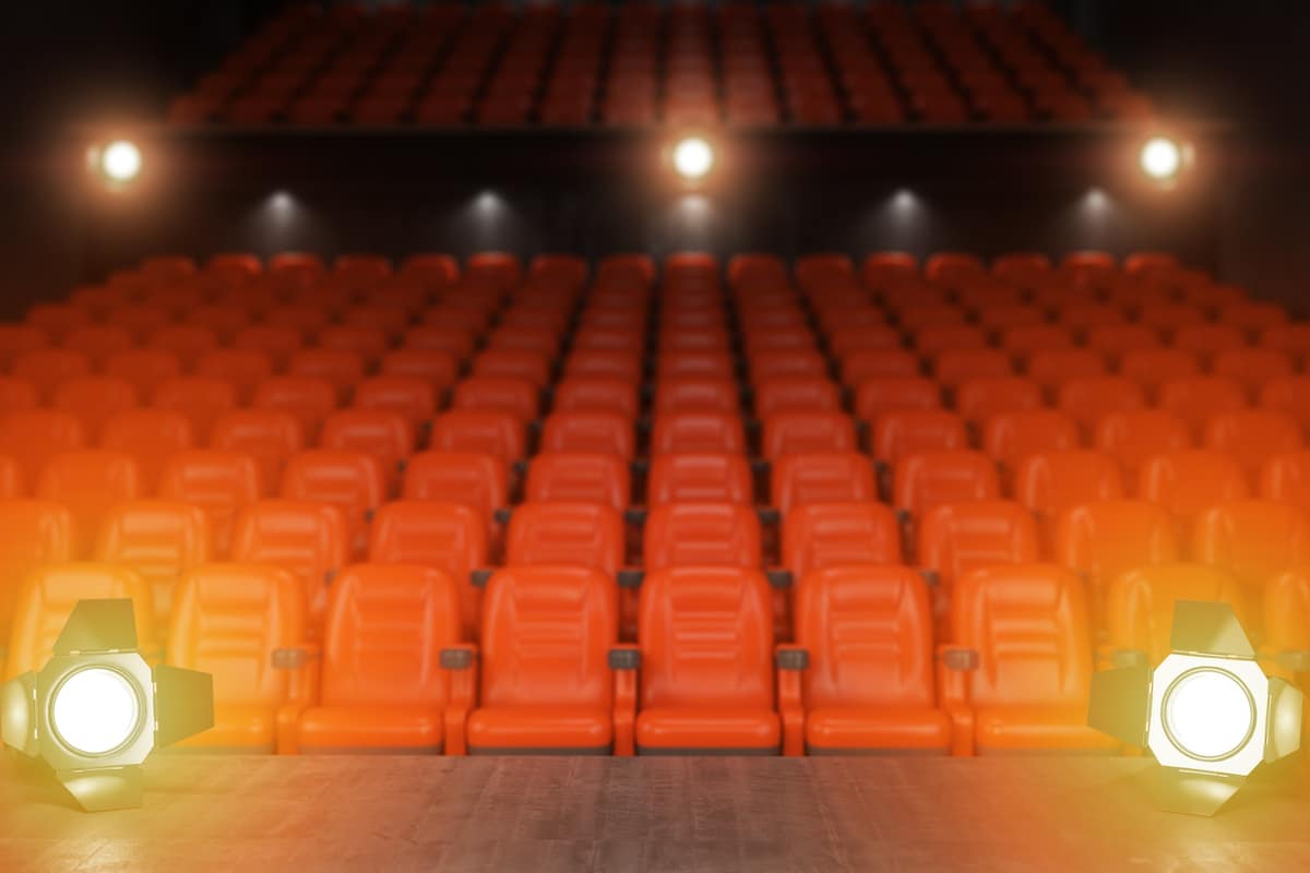 Blick von der Bühne in einen leeren Theatersaal mit roten Sitzen und Scheinwerfern