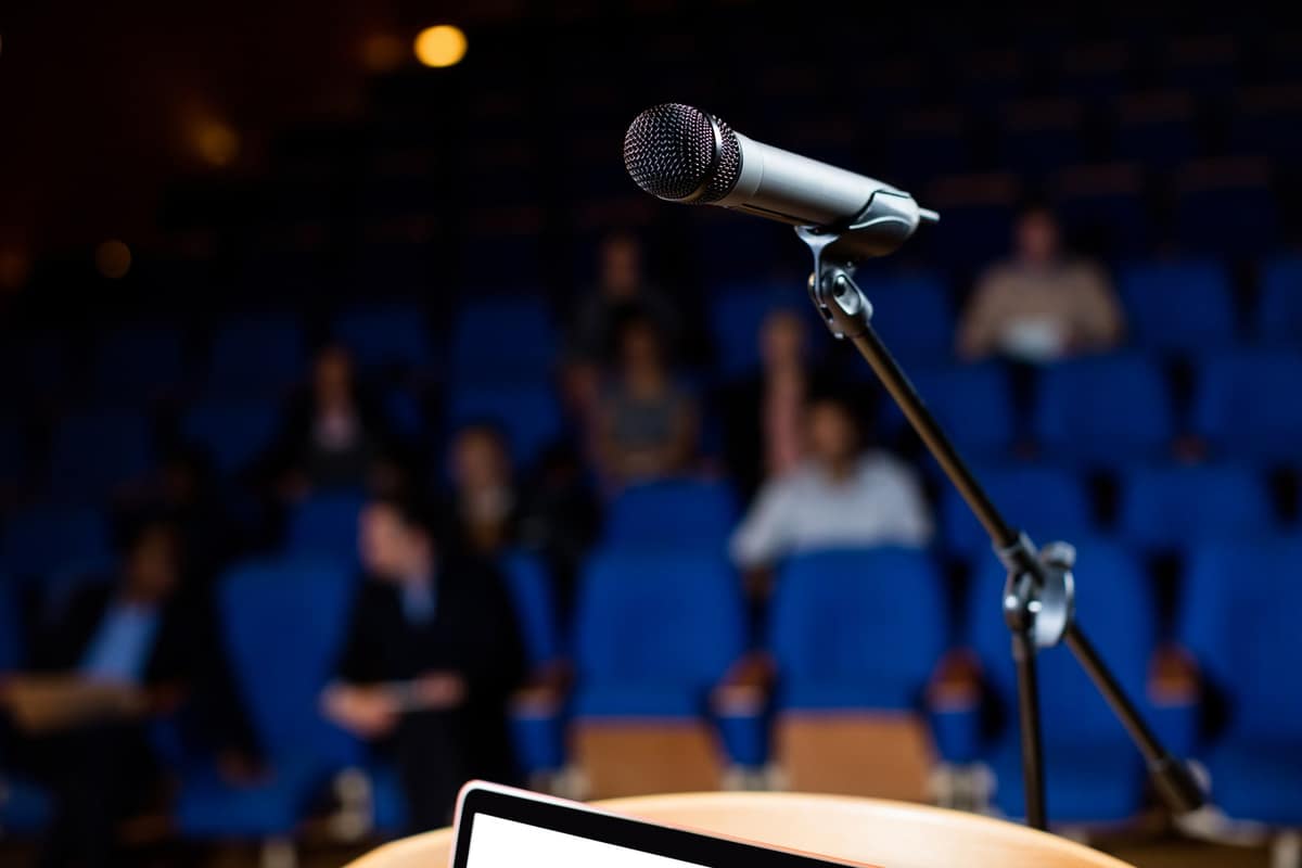 Mikrofon am Rednerpult vor einem Publikum im Saal